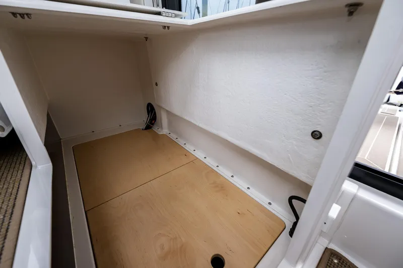 Slide: The Image of Storage compartment in a 2022 Nimbus C11 boat, featuring a wooden base and white interior. - 27
