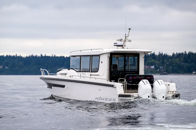 Slide: The Image of 2022 Nimbus C11 boat cruising on a calm lake with forested shoreline. - 5