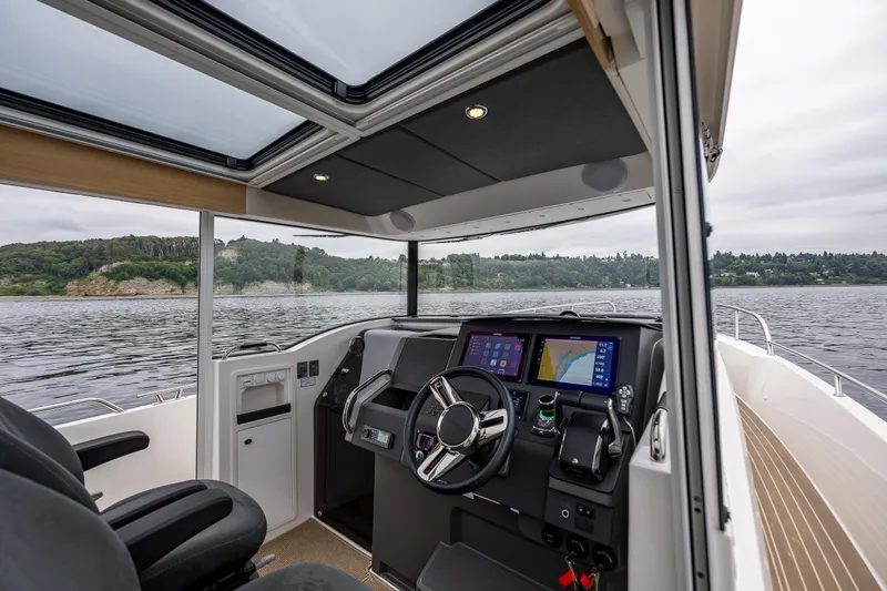 Slide: The Image of Interior of 2022 Nimbus C11 boat with modern dashboard and scenic water view. - 8