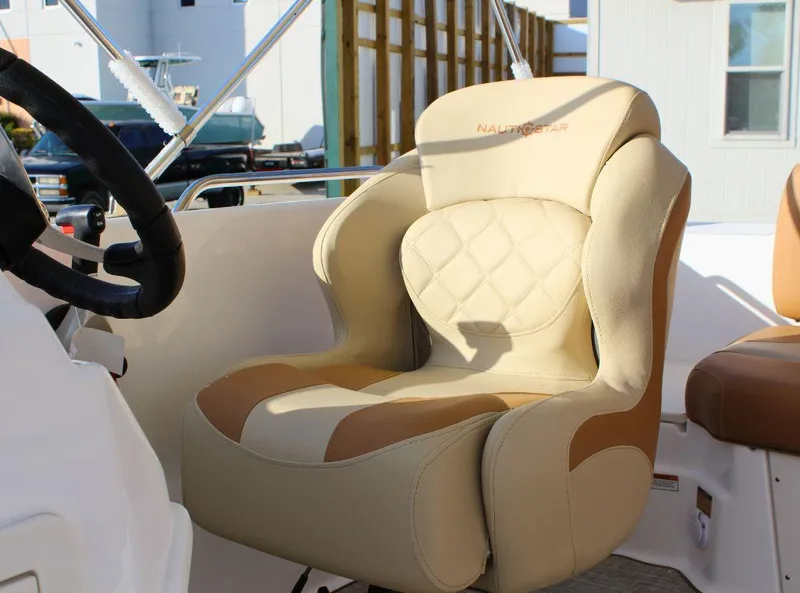 Slide: The Image of 2024 NauticStar 193 SC boat seat, beige and tan upholstery, steering wheel visible. - 11