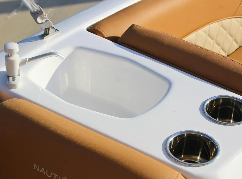 Slide: The Image of 2024 NauticStar 193 SC boat interior with cup holders and tan seating. - 13
