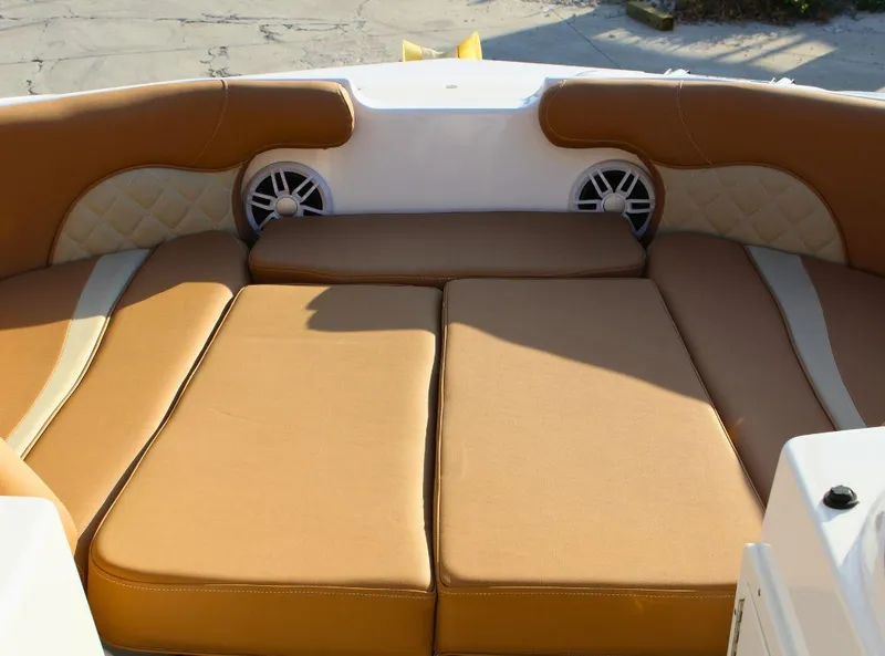 Slide: The Image of 2024 NauticStar 193 SC boat interior with tan cushioned seating and built-in speakers. - 16