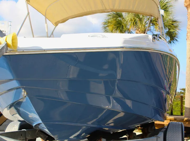 Slide: The Image of 2024 NauticStar 193 SC boat with blue hull and canopy, parked outdoors. - 3