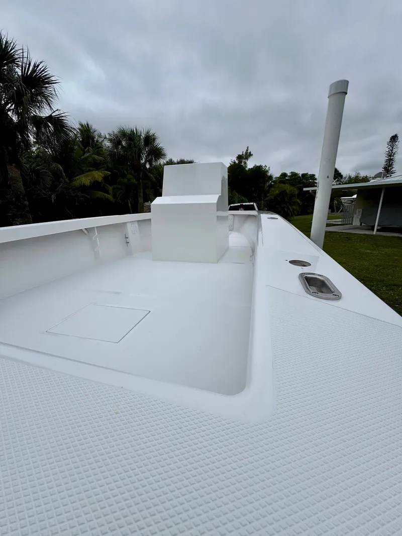Slide: The Image of 2025 Rambo 27 boat deck, white finish, surrounded by tropical trees under cloudy sky. - 21