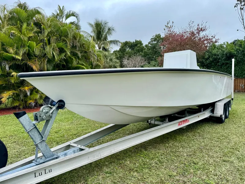 Slide: The Image of 2025 Rambo 27 boat on trailer, parked on grass with lush greenery background. - 6