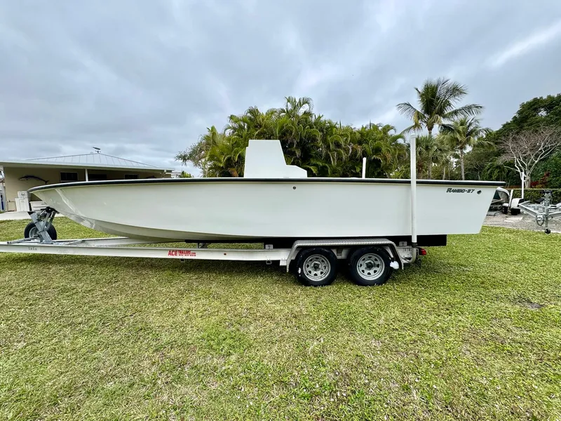 Slide: The Image of 2025 Rambo 27 boat on trailer, parked on grass, with palm trees in background. - 7