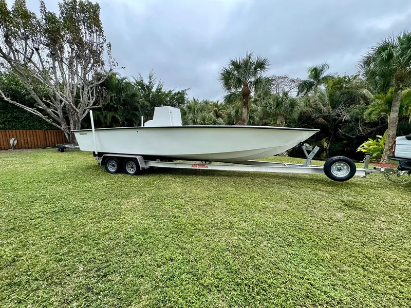 Slide: The Image of Rambo 27 boat on trailer, grassy yard, palm trees, overcast sky, 2025 model. - 8