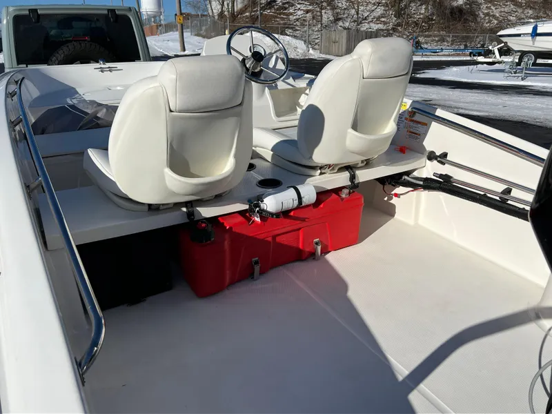 Slide: The Image of 2016 Boston Whaler 150 Super Sport interior with white seats and red storage box. - 15
