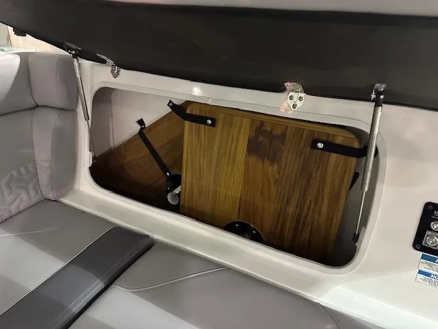 Slide: The Image of 2025 Regal LS36 boat storage compartment with wooden interior and cushioned seating. - 23