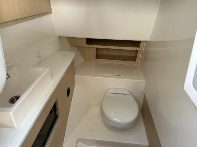 Slide: The Image of 2025 Regal LS36 boat interior bathroom with sink and toilet, featuring modern design and light wood accents. - 28