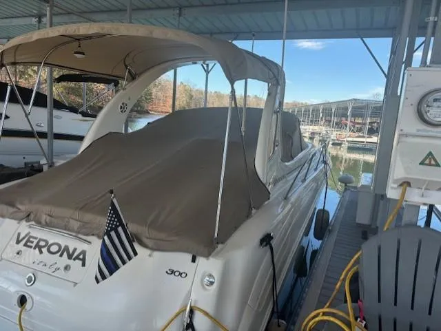 Slide: The Image of 2005 Sea Ray 300 Sundancer docked, covered, with American flag, marina in background. - 2