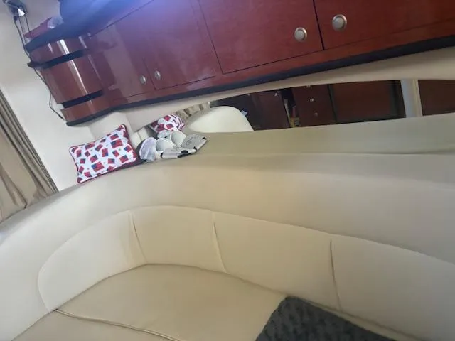 Slide: The Image of Interior of 2005 Sea Ray 300 Sundancer with beige seating and wooden cabinets. - 23