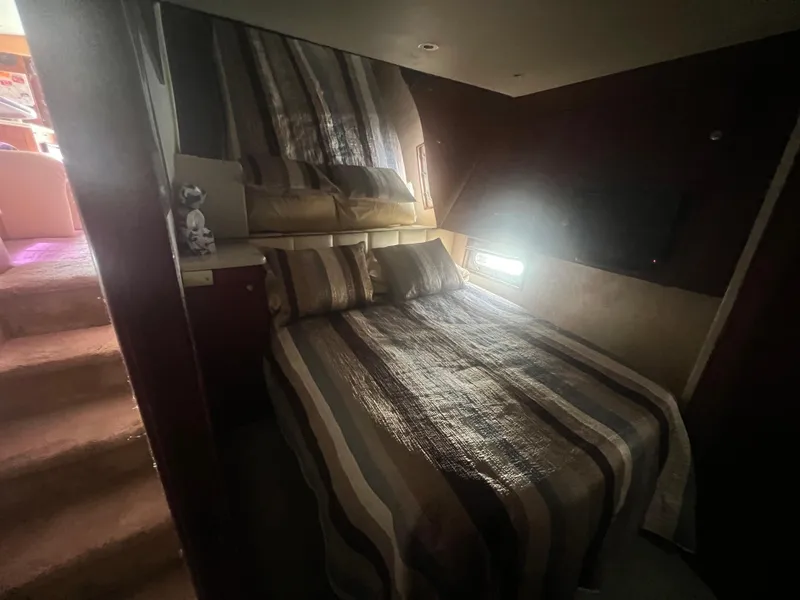 Slide: The Image of 1996 Ocean Yachts 48 Super Sport bedroom with striped bedding and soft lighting. - 24