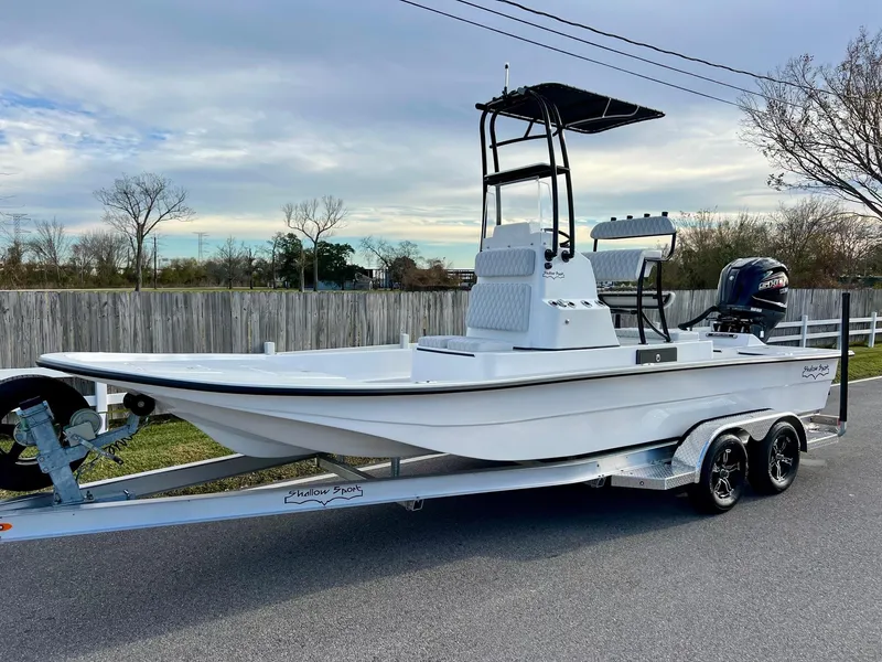 The Image of 2025 Shallow Sport 24 Sport boat on trailer, parked on a road, under a cloudy sky. - 1