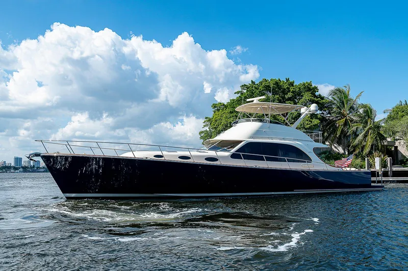 Slide: The Image of 2026 Palm Beach Motor Yachts PB65 cruising on a sunny day, surrounded by lush greenery. - 24