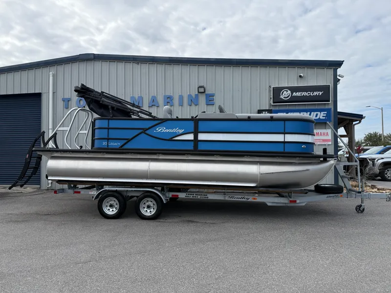 Slide: The Image of 2025 Bentley Pontoons 20 Legacy boat on trailer outside marine dealership. - 2