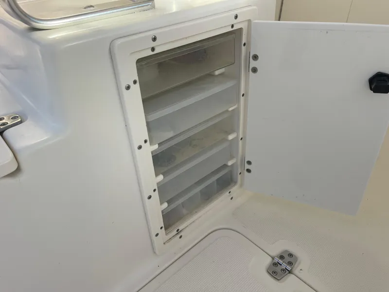 Slide: The Image of Open storage compartment on 2003 Pursuit 2870 Walkaround boat, featuring multiple shelves. - 16