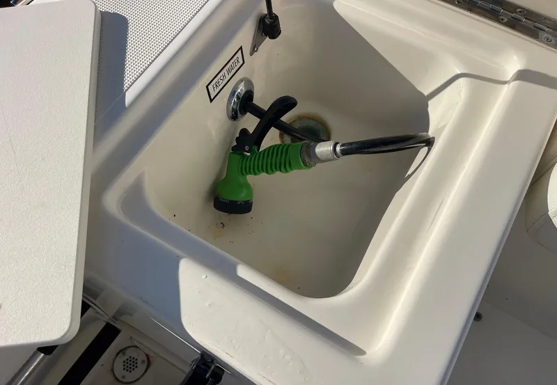 Slide: The Image of 2003 Pursuit 2870 Walkaround boat sink with green hose attachment. - 21