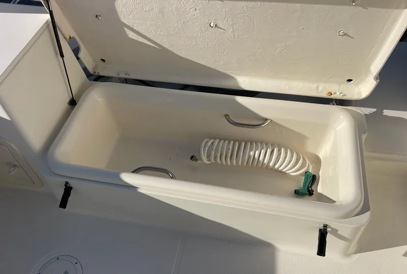Slide: The Image of Open storage compartment on 2003 Pursuit 2870 Walkaround boat with coiled hose inside. - 22