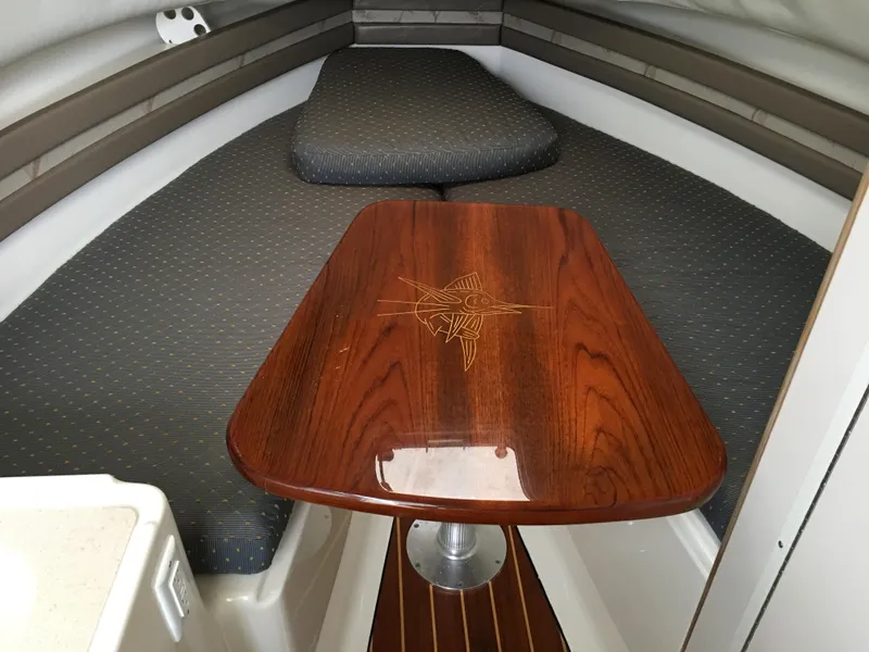Slide: The Image of 2003 Pursuit 2870 Walkaround cabin interior with wooden table and cushioned seating. - 34