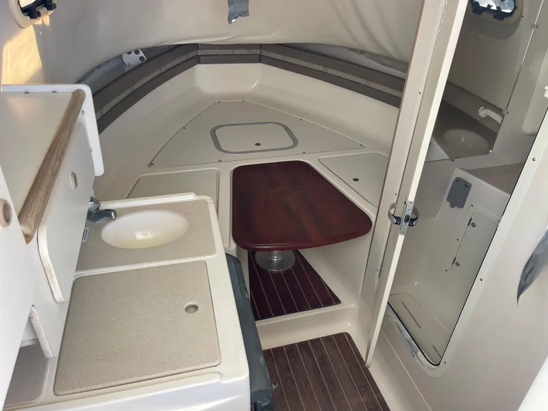 Slide: The Image of 2003 Pursuit 2870 Walkaround cabin interior with sink, table, and compact bathroom. - 35