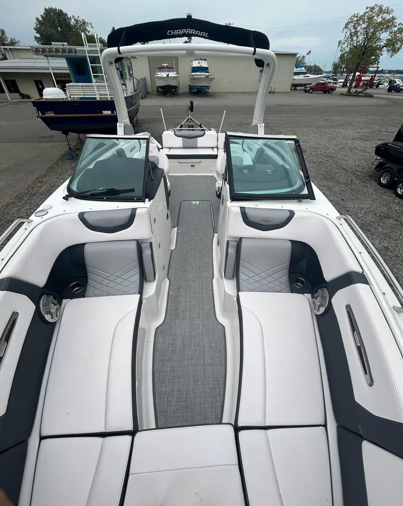 Slide: The Image of 2019 Chaparral 277 SSX boat interior with white and gray seating, docked outdoors. - 28