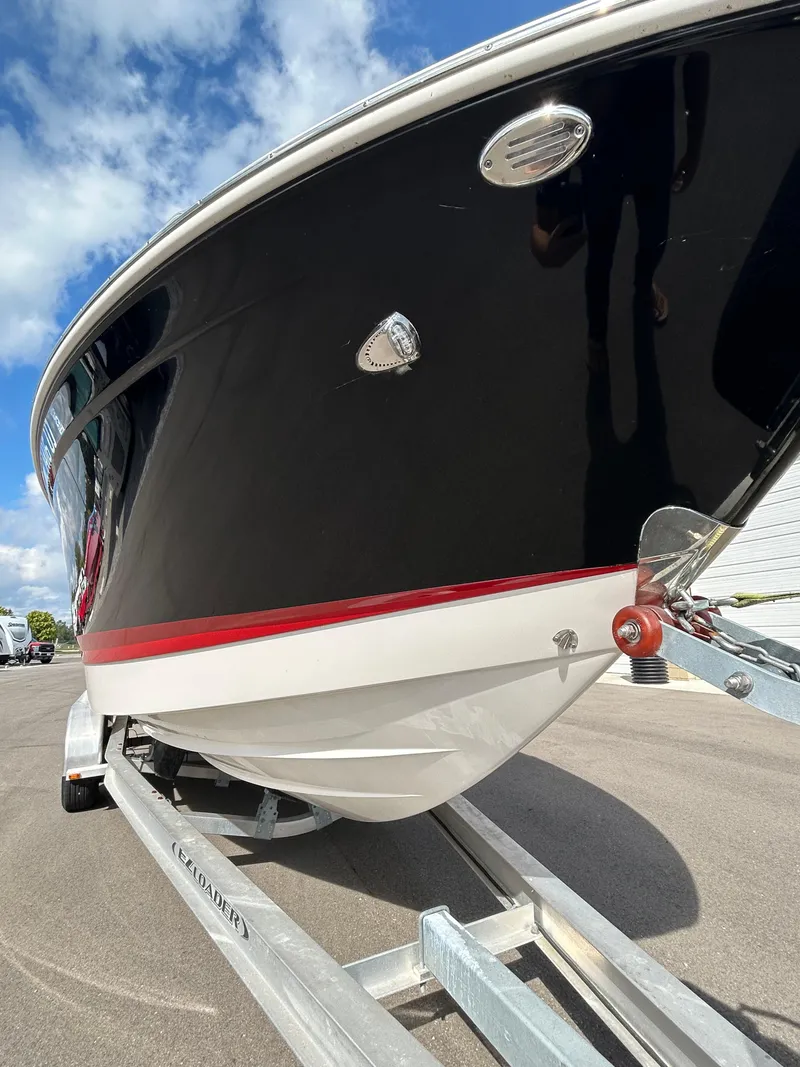 Slide: The Image of 2019 Chaparral 277 SSX boat on trailer, black hull with red stripe, under blue sky. - 3