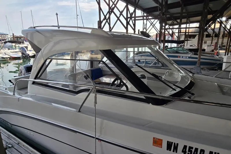Slide: The Image of 2022 Beneteau Antares 7 boat docked in a marina under a shelter. - 7