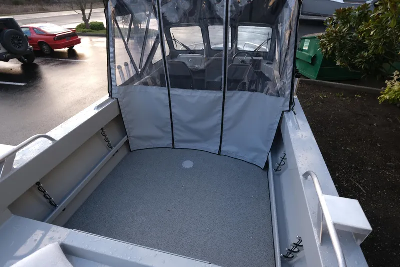 Slide: The Image of 2025 Hewescraft 180 Sportsman boat interior with canopy, parked outdoors. - 6