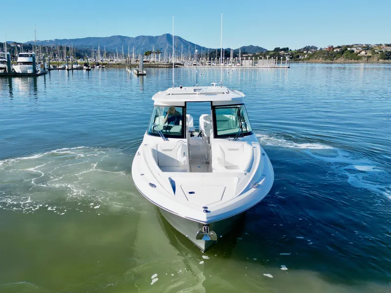 Slide: The Image of 2025 Tiara Yachts 34 LX cruising in a serene marina with mountain backdrop. - 21