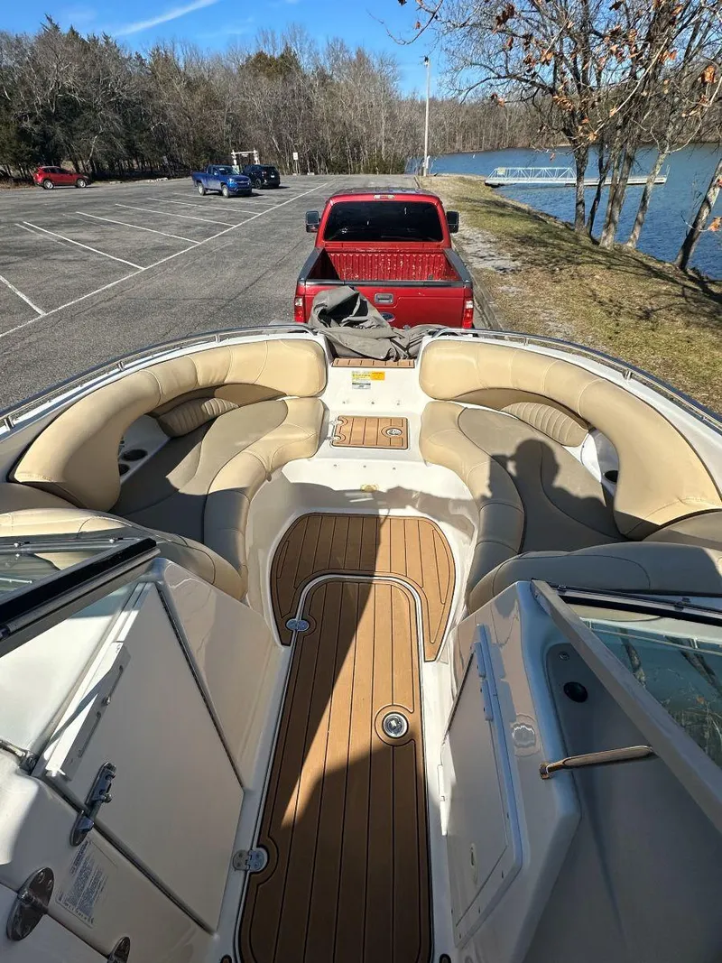 Slide: The Image of 2010 NauticStar 230DC Sport Deck boat interior with tan seating, parked near a lake. - 10