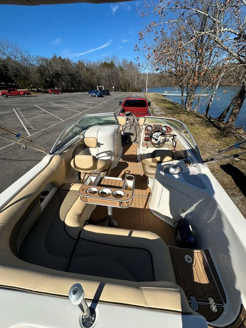 Slide: The Image of 2010 NauticStar 230DC Sport Deck boat interior with seating and steering, parked near a lake. - 13