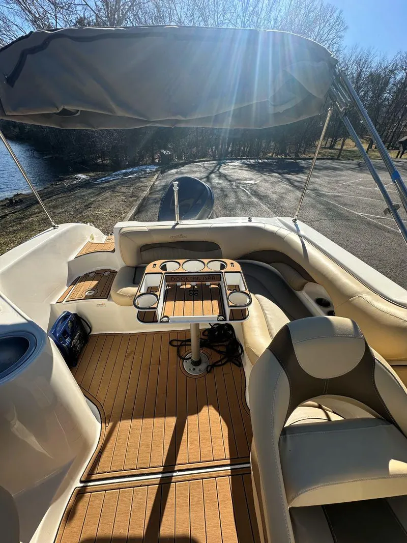 Slide: The Image of 2010 NauticStar 230DC Sport Deck boat with seating and table, under sunny skies. - 14