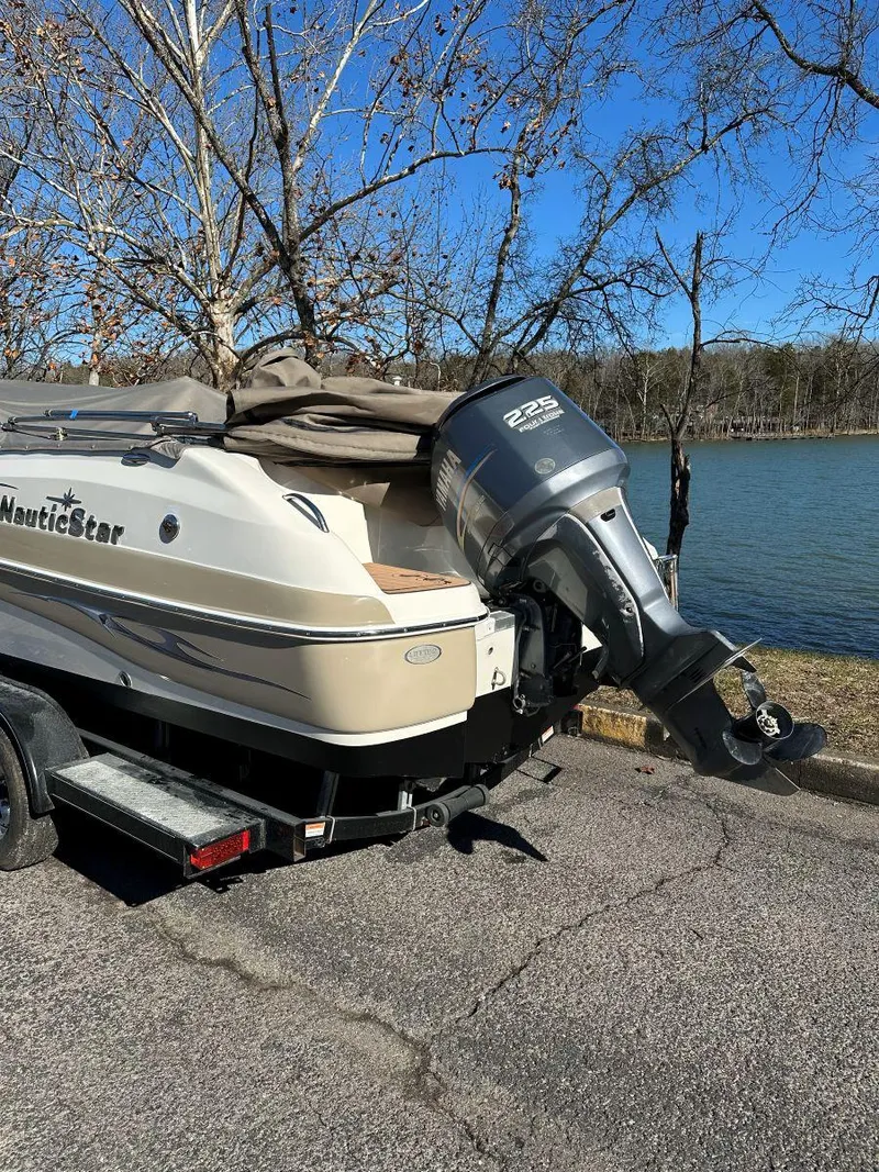 Slide: The Image of 2010 NauticStar 230DC Sport Deck boat with outboard motor, parked near a lake. - 3