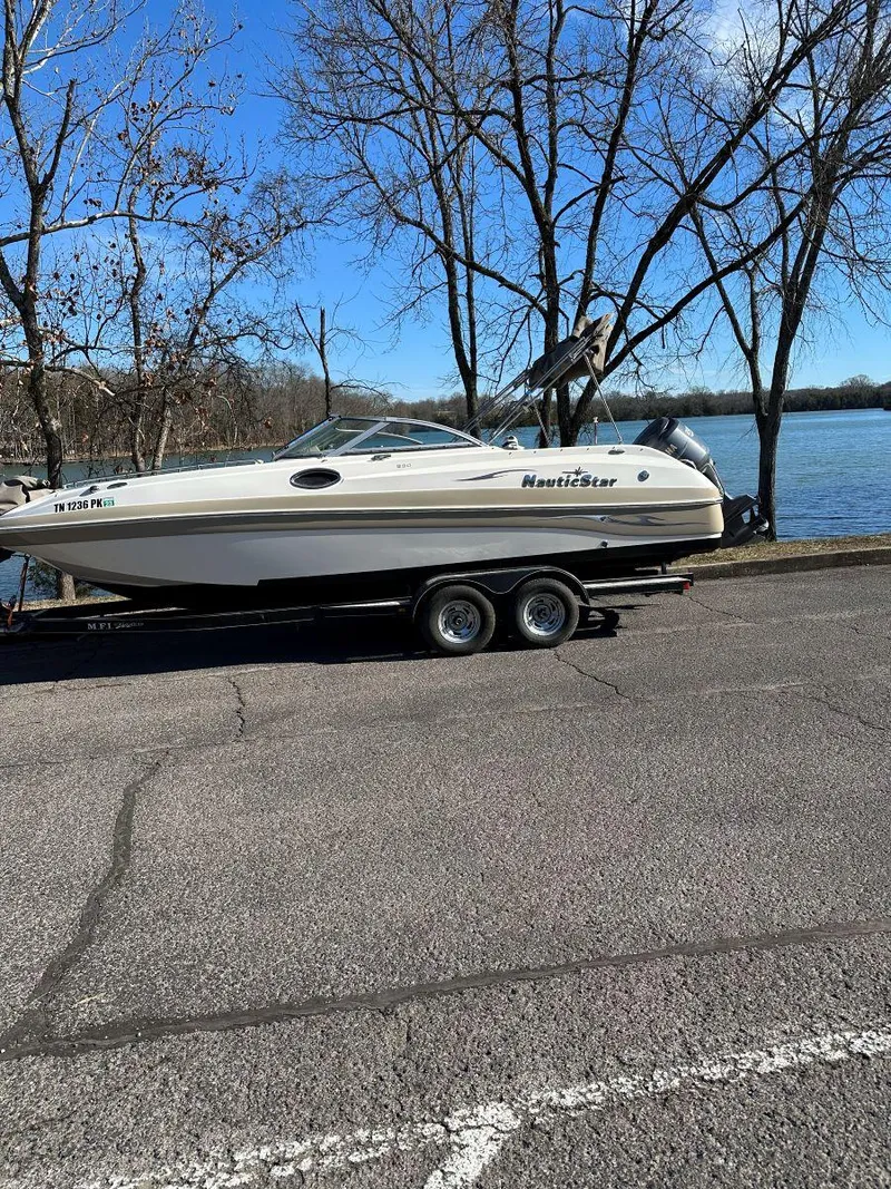 Slide: The Image of 2010 NauticStar 230DC Sport Deck boat on trailer by a lake. - 8