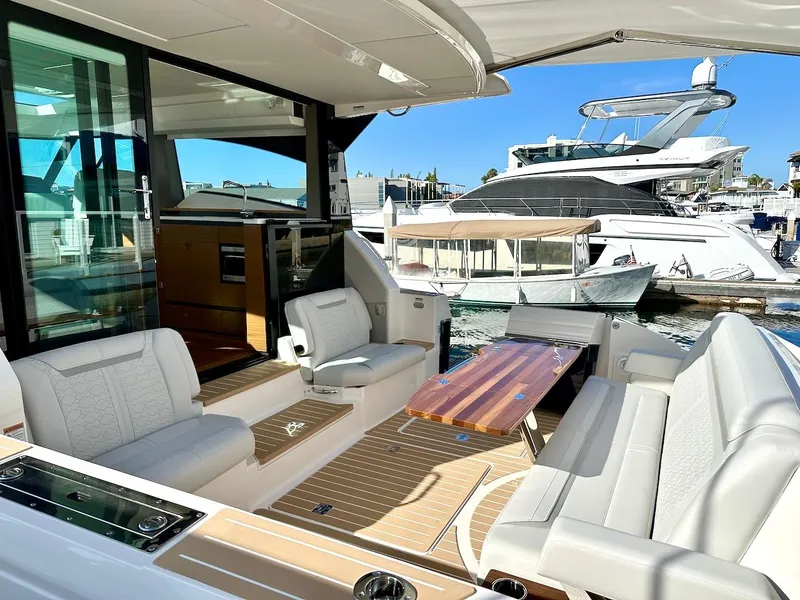 Slide: The Image of Luxurious 2025 Tiara Yachts 48 LE with elegant seating and wooden table in marina setting. - 11