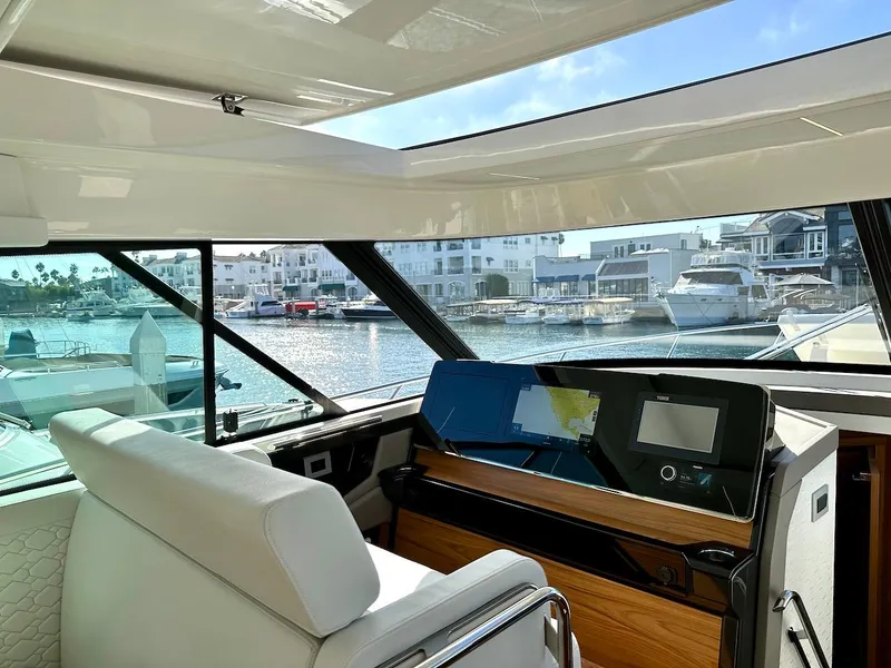 Slide: The Image of Interior view of 2025 Tiara Yachts 48 LE, showcasing helm and marina backdrop. - 43
