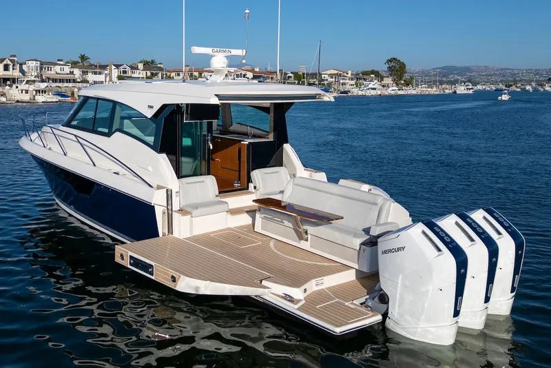 Slide: The Image of 2025 Tiara Yachts 48 LE with triple Mercury engines on a serene waterfront. - 7