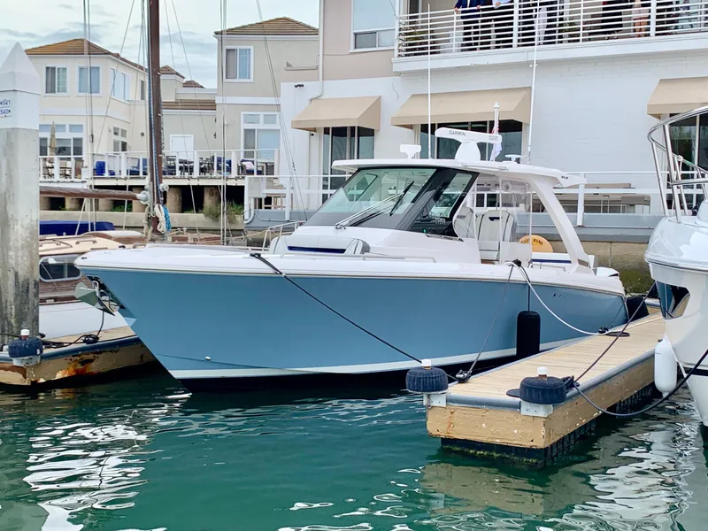 Slide: The Image of 2024 Tiara Sport 34LS boat docked at a marina, featuring a sleek blue hull. - 0