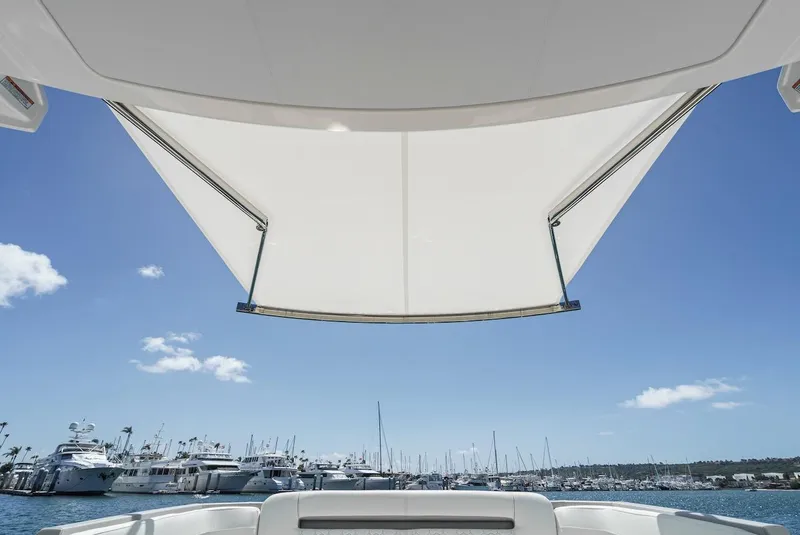Slide: The Image of 2024 Tiara Yachts 38 LS with sunshade, overlooking marina and clear blue sky. - 32
