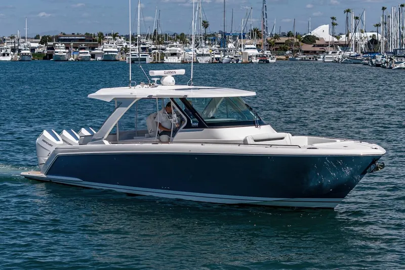 Slide: The Image of 2024 Tiara Yachts 38 LS cruising in a marina with sailboats in the background. - 7