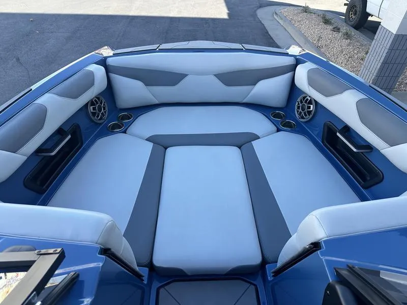 Slide: The Image of 2022 Axis A24 boat interior with blue and gray seating, cup holders, and speakers. - 14