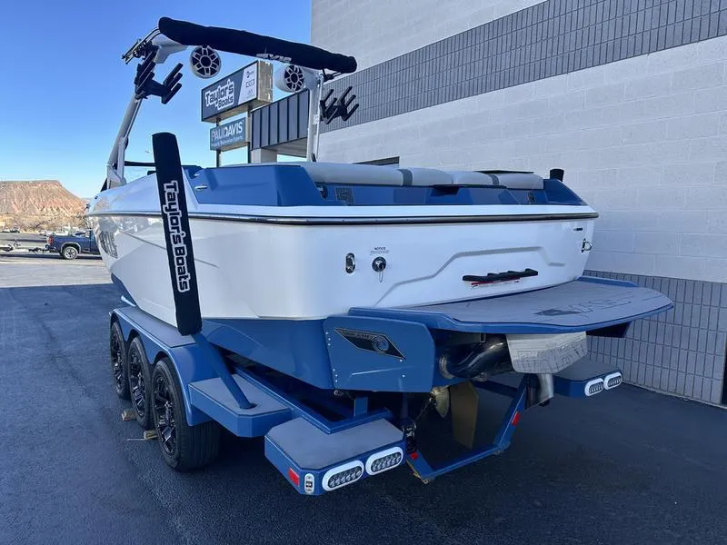 Slide: The Image of 2022 Axis A24 boat on trailer, blue and white, parked near a building. - 4