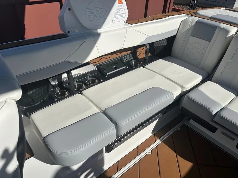 Slide: The Image of 2025 Malibu 23 LSV boat interior with white and gray seating and cup holders. - 16