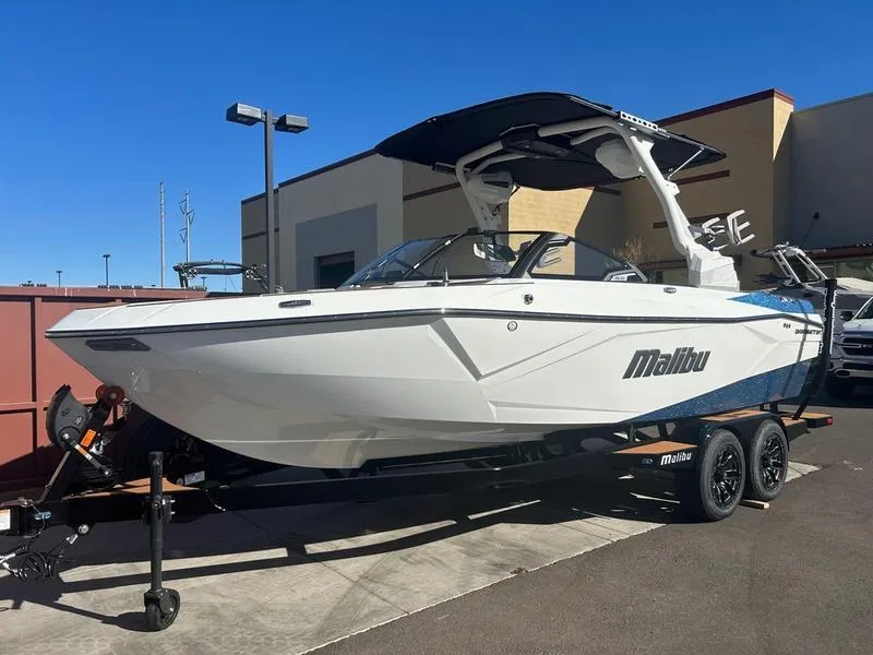 Slide: The Image of 2025 Malibu 23 LSV boat on trailer, parked outdoors under clear blue sky. - 3