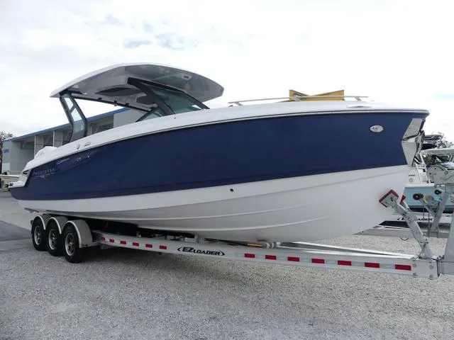 Slide: The Image of 2025 Monterey Elite 30 OB boat on trailer, blue and white design, parked outdoors. - 1