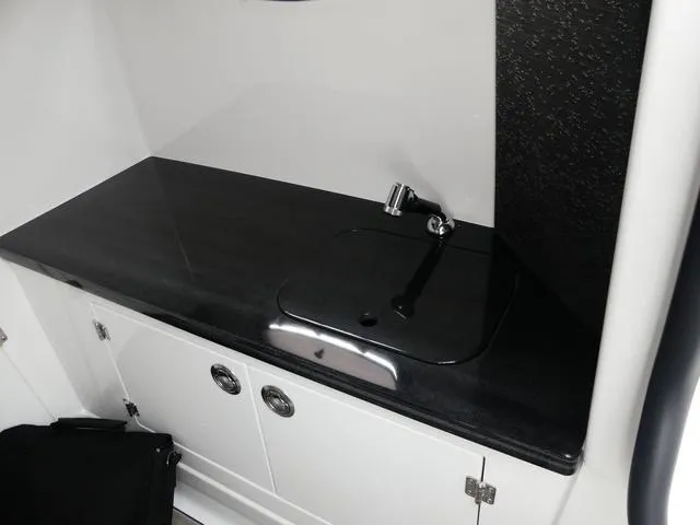 Slide: The Image of 2025 Monterey Elite 30 OB boat interior with sleek black countertop and modern sink. - 32