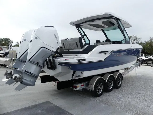 Slide: The Image of 2025 Monterey Elite 30 OB boat with triple-axle trailer, featuring a sleek blue and white design. - 7