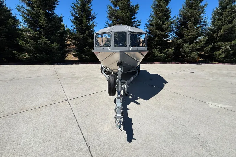 Slide: The Image of 2025 Spartan 185 Astoria boat on trailer, parked on concrete with trees in background. - 6