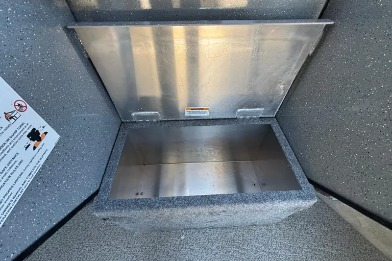 Slide: The Image of Open storage compartment in 2025 Spartan 185 Astoria boat, featuring metallic interior and safety instructions. - 42